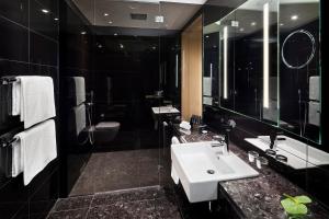 Un baño con lavabo, inodoro y espejo. en Melia Vienna, en Viena