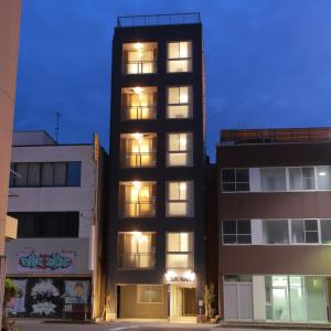 a tall building with lit windows in a city at W&M House in Kanazawa