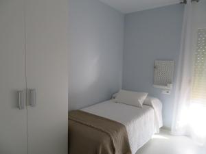 Habitación blanca pequeña con cama y ventana en Alcañiz Flats II, en Alcañiz