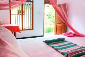 a bed with a blanket on it with a window at Lilac Garden Mirissa in Weligama