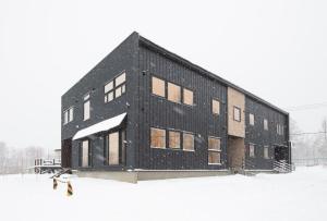 a black building with snow on it in the snow at Hirafu Tomten in Niseko