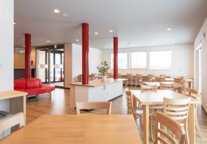 a restaurant with wooden tables and chairs and red chairs at Hirafu Tomten in Niseko