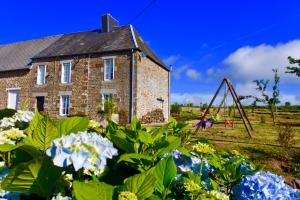 an old brick house with a swing and flowers at L'Auberdiere in Saint-Jean-des-Essartiers