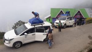 a group of people standing around a white car with a tent on top at Magnolia Homestay in Sombāri