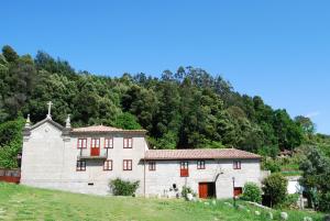 un antiguo edificio de piedra en una colina con árboles en Quinta Casa da Fonte en Vieira do Minho
