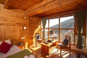 a bedroom with a large window in a log cabin at Zostel Homes Cheog (Shimla) in Cheog
