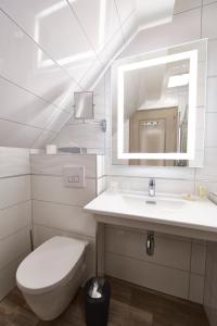 a bathroom with a toilet and a sink and a mirror at Best Western Plus Au cheval Blanc à Mulhouse in Baldersheim