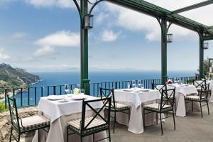 a dining area with tables and chairs and umbrellas at Palazzo Avino in Ravello