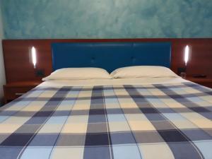 a bed with a blue and white checkered blanket at B&B IL GHIRO in Roccaraso
