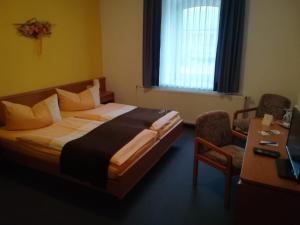a hotel room with a bed and a desk and a desk at Kyffhäuserhotel "Goldene Aue" in Wallhausen