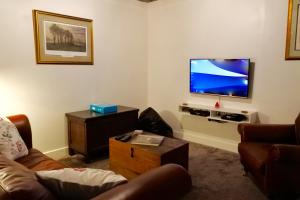 ein Wohnzimmer mit einem Sofa und einem Flachbild-TV in der Unterkunft L'Auberdiere in Saint-Jean-des-Essartiers