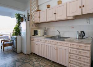 a kitchen with white cabinets and a sink and a refrigerator at Apartment Evaggelia Sea View in Skala Marion