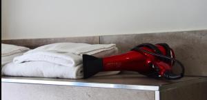un sèche-cheveux rouge assis sur une étagère à côté d'un lit dans l'établissement Casa Isabela luxury rooms, à Melfi