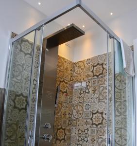 ducha con puerta de cristal y pared de azulejos en Casa Isabela luxury rooms en Melfi