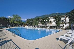 a large swimming pool with white chairs in a resort at Camping Hotel Au Lac De Como in Sorico