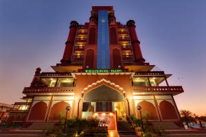 a building with a clock tower at dusk at Whispering Palms Hotel Jaipur in Jaipur