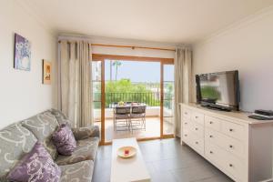 Il comprend un salon avec un canapé, une télévision et un balcon. dans l'établissement Apartamentos CARABELA BEACH Alcudia, à Alcúdia