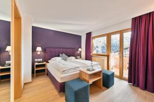ein Schlafzimmer mit einem Bett mit einer lila Wand in der Unterkunft Hotel Petersboden in Lech am Arlberg