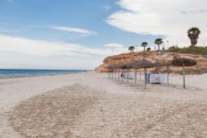 een strand met parasols en stoelen en de oceaan bij Apartment Vistamar II in Campoamor