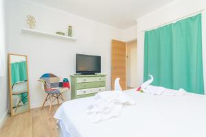 a bedroom with a white bed and a television at Es Baladre in Port d'Alcudia +20 photos