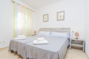 a white bedroom with two beds with towels on them at Lluna Home in Colonia Sant Jordi
