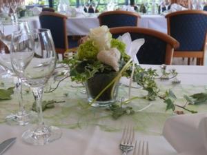 a table with glasses and a vase with flowers on it at Stichwehs Hotel am Bahnhof in Elze