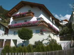 a white house with purple flowers on the balcony at Gästehaus Walch in Fendels