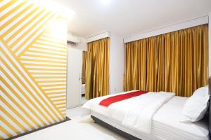 a bedroom with a large bed and yellow curtains at RedDoorz near IPB Dramaga Bogor in Bogor