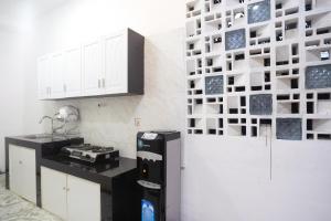 a kitchen with white cabinets and a black and white wall at RedDoorz near IPB Dramaga Bogor in Bogor