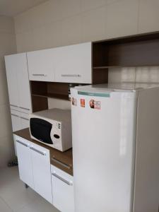 a white kitchen with a microwave and a refrigerator at Imperial Park in Cornélio Procópio