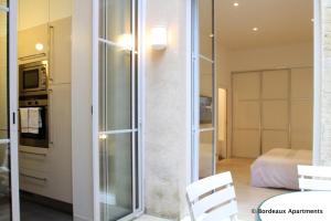 Zimmer mit einer Glasschiebetür und einem Schlafzimmer in der Unterkunft Bordeaux City Gardens in Bordeaux