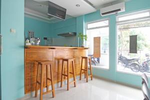 a kitchen with blue walls and a bar with stools at RedDoorz near Solo Balapan Station in Solo