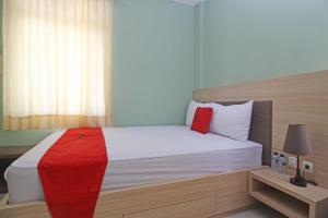 a bedroom with a bed with a red blanket on it at RedDoorz near Solo Balapan Station in Solo