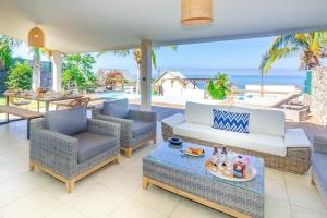 eine Terrasse mit einem Sofa, Stühlen und Meerblick in der Unterkunft Villa Élysée - Vue mer et piscine à Saint-Gilles in Grand Fond