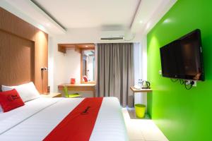 Habitación de hotel con cama con pared verde en RedDoorz Apartment at Bogor Valley, en Bogor