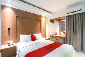a hotel room with a large bed with red pillows at RedDoorz Apartment at Bogor Valley in Bogor