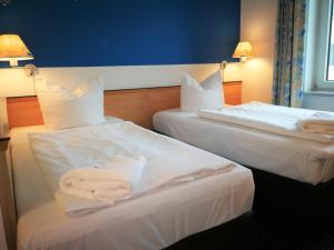 Hotel NEAR BY في هانوفر: سريرين في غرفة الفندق عليها مناشف