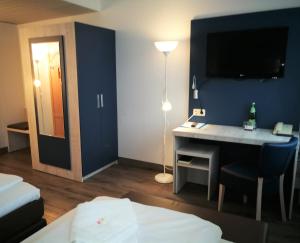 ein Hotelzimmer mit einem Schreibtisch und einem TV an der Wand in der Unterkunft Hotel NEAR BY in Hannover