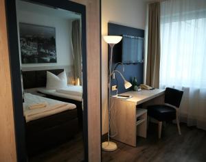 Pokój hotelowy z biurkiem, łóżkiem i lustrem w obiekcie Hotel NEAR BY w Hanowerze