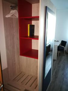 um armário com prateleiras vermelhas e um espelho em Hotel NEAR BY em Hanôver