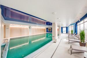 an indoor swimming pool in a building with chairs at City Center Apartments SPA & Wellness in Gdańsk