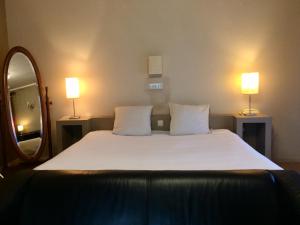- une chambre avec un grand lit blanc et deux lampes dans l'établissement Hotel La Venerie, à Virton