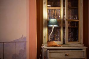 ルッカにあるホテル アッラ コルテ デッリ アンジェリの部屋のドレッサーの上に座るランプ