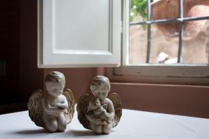 two angel figurines sitting on a table next to a window at Hotel Alla Corte degli Angeli in Lucca