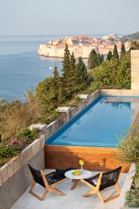 een zwembad met twee stoelen en een tafel naast een zwembad bij Villa Paulina in Dubrovnik