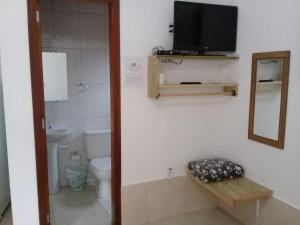 a bathroom with a toilet and a tv on a wall at Chalé Da Fran in Maresias