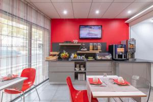 une salle à manger avec des murs rouges, une table et des chaises dans l'établissement Lagrange Apart'Hotel l’Escale Marine, à La Rochelle