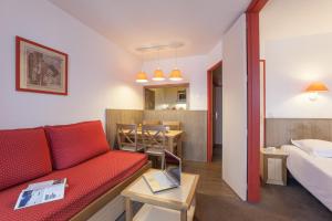 un salon avec un canapé rouge et une chambre dans l'établissement Résidence Pierre & Vacances Le Chamois Blanc, à Chamonix-Mont-Blanc