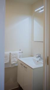 a white bathroom with a sink and a mirror at Hôtel Vauban in Livry-Gargan