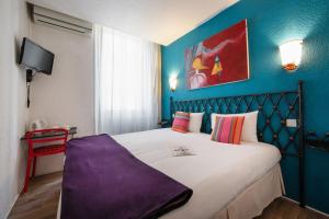 a bedroom with a large bed with a blue wall at Hôtel Brimer Cannes in Cannes